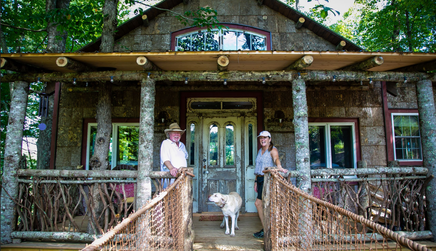 Family and dog standing in front of log cabin home